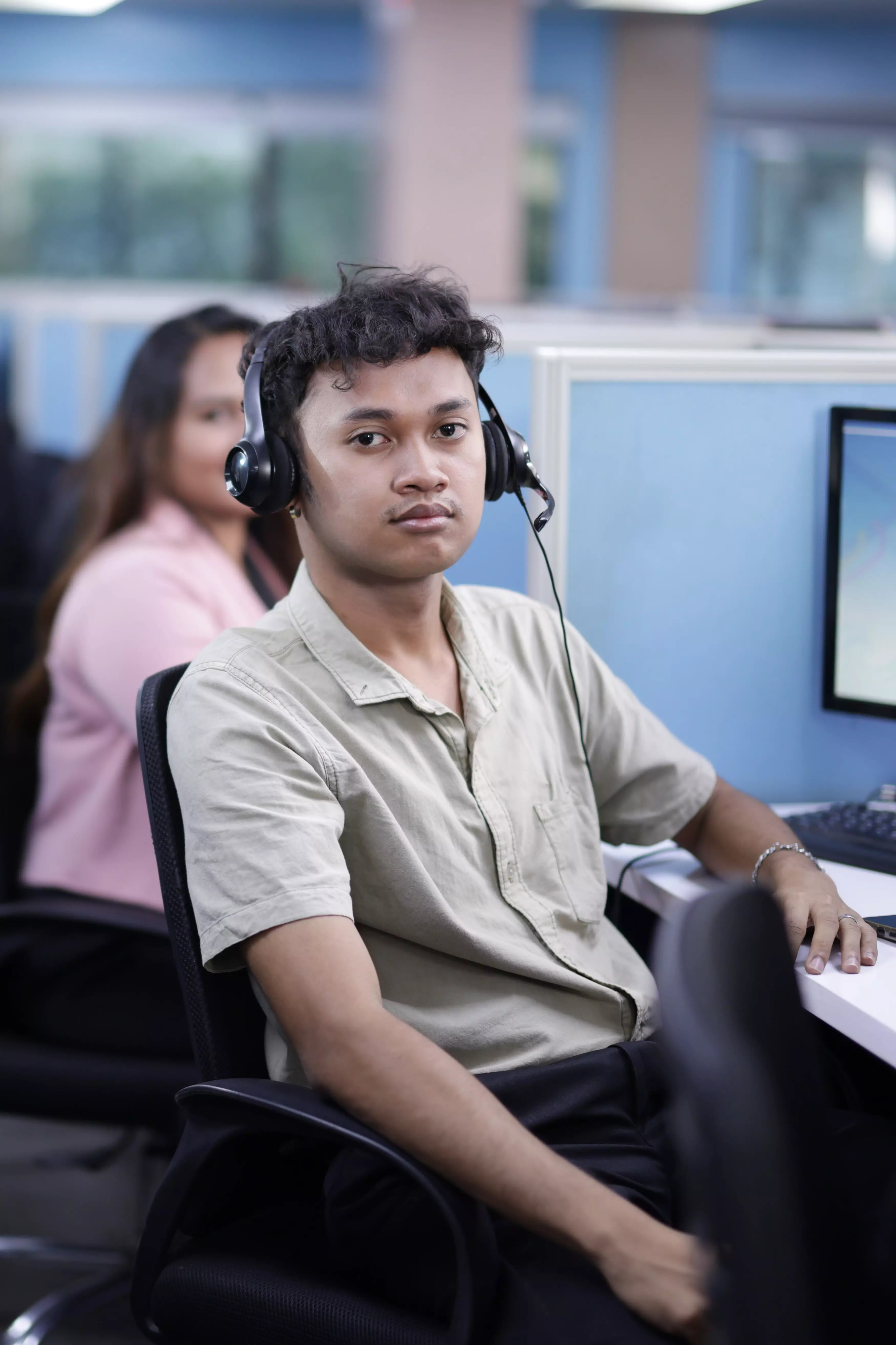 Male employee sitting in his cubicle looking at the camera.